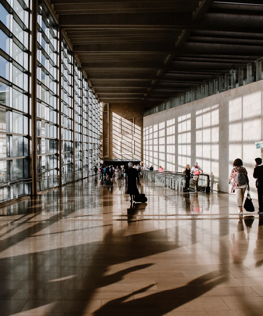 Viajantes com malas num terminal de aeroporto cheio de sol