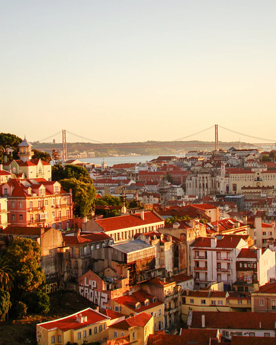 Vista ao fim da tarde sobre os telhados de Lisboa, com a Ponte 25 de Abril ao fundo